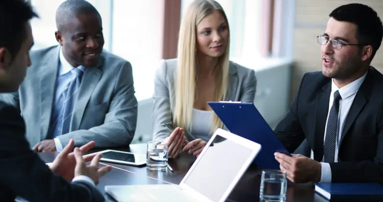 How to tell a story: image of a man telling his colleagues a story around a boardroom table